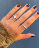 Hand wearing two diamond rings with a dark background