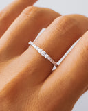 Diamond ring on a person's finger with a neutral background