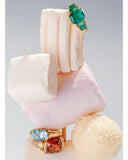 Two rings with gemstones displayed on a pink cushion against a light gray background. Mara Megelea Prestige Magazine